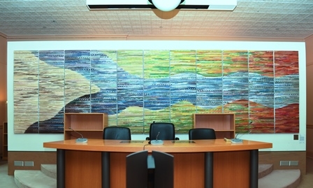 A tapestry depicting a river during multiple seasons hangs on a wall.