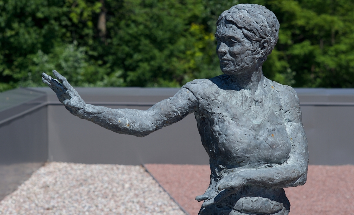 A stainless steel statue depicting a person doing a t'ai chi movement.